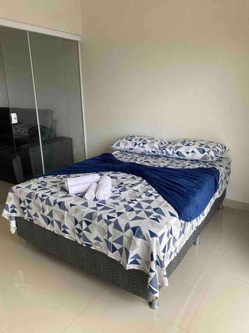 a bed with blue and white comforter in a room at Flat Delior 07 - Parada do Jalapão, rodoviária, faculdades e Aeroporto in Palmas