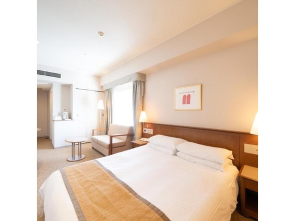 Pokój hotelowy z łóżkiem i krzesłem w obiekcie Hotel Terrace The Square Hitachi - Vacation STAY 21910v w mieście Hitachi