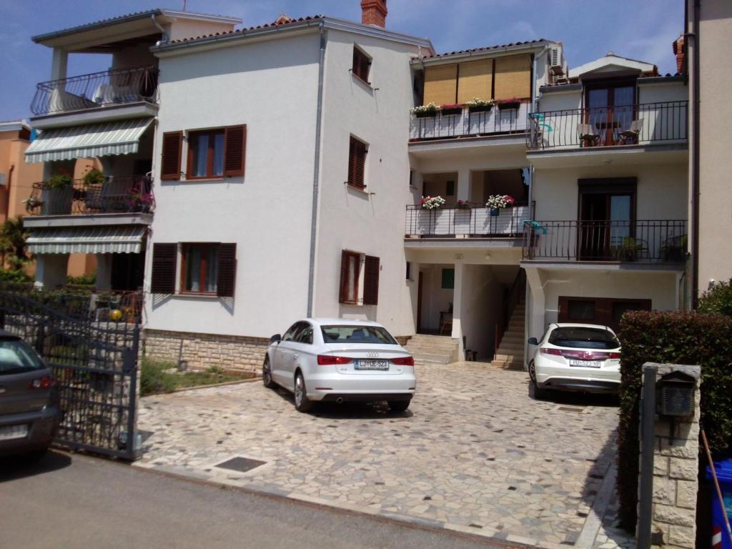 due auto parcheggiate in un parcheggio di fronte a un edificio di Apartment JAL a Rovigno (Rovinj)