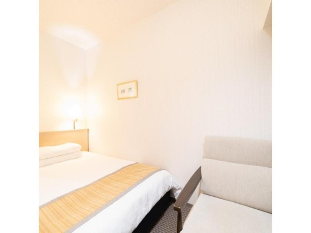 um pequeno quarto com uma cama e uma cadeira em Hotel Terrace The Square Hitachi - Vacation STAY 21902v em Hitachi