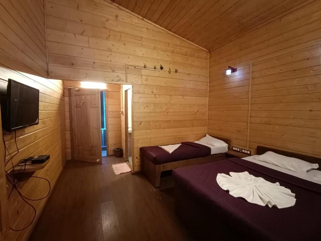 pokój z dwoma łóżkami i telewizorem w obiekcie Praveen's Wood house Kodaikanal Vattakanal w mieście Kodaikānāl