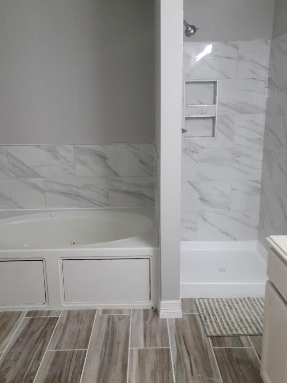 a bathroom with a white tub and marble walls at Fresh CrashPads in Houston