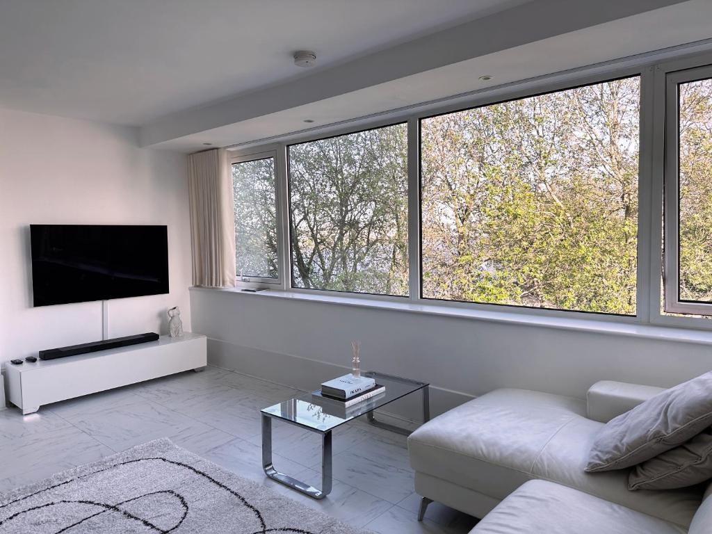 a white living room with a couch and a tv at Stylish & Cosy Nest near River Thames in London