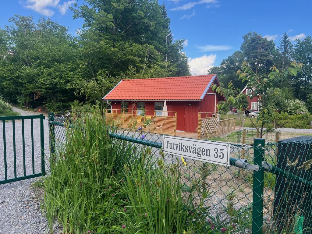 Vendelsö的住宿－Tinyhouse Tutviksvägen 35B，红房子前的栅栏上的一个标志