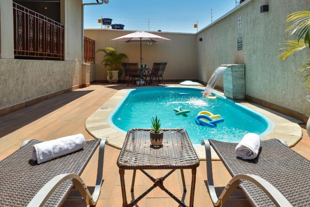 a swimming pool with two chairs and a table and a table at CASA CHARME DO CERRADO in Pirenópolis