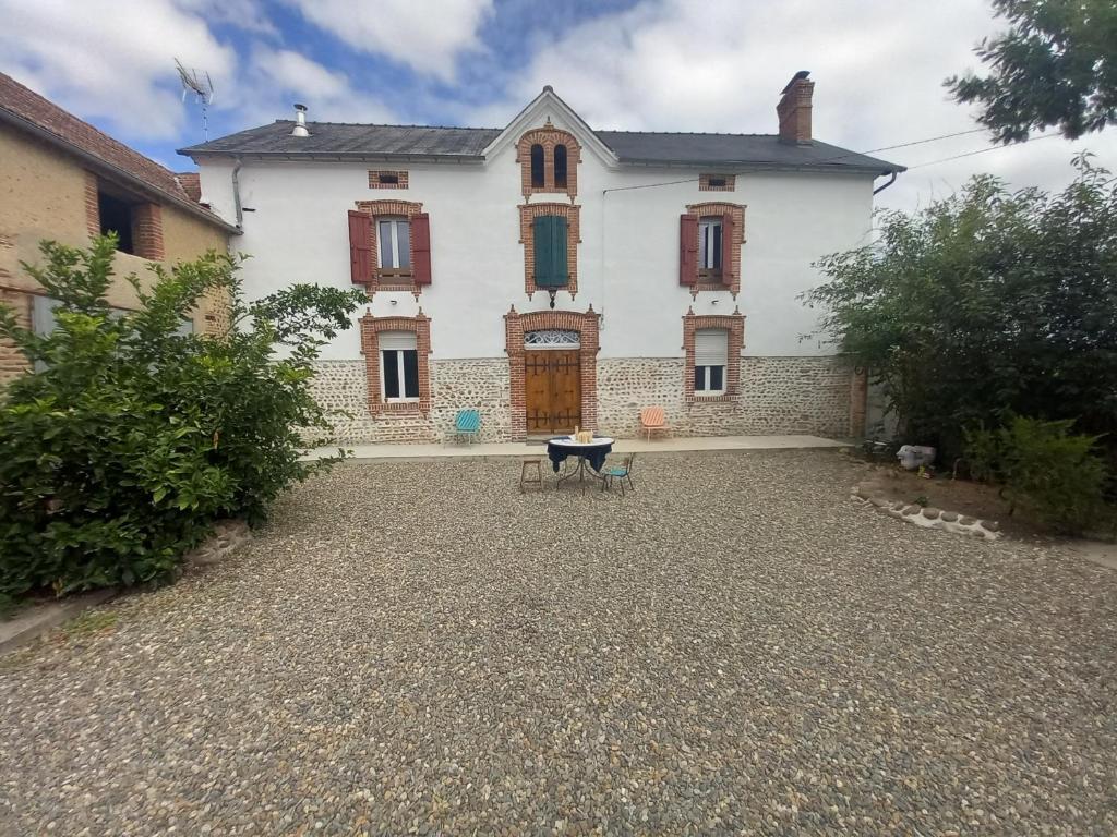 una gran casa blanca con una mesa delante en Les Jardins de l'Imaginaire, en Monségur