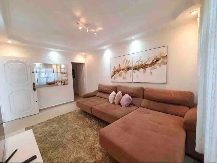 ein Wohnzimmer mit einem braunen Sofa und einem Gemälde in der Unterkunft Casa maravilhosa e completa, ótima localização in São Paulo