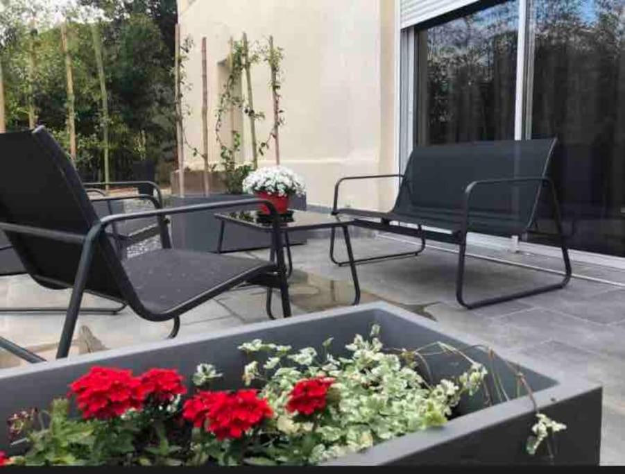 a patio with two chairs and a planter with red flowers at Très beau T2 dans mas . in Boisset-et-Gaujac