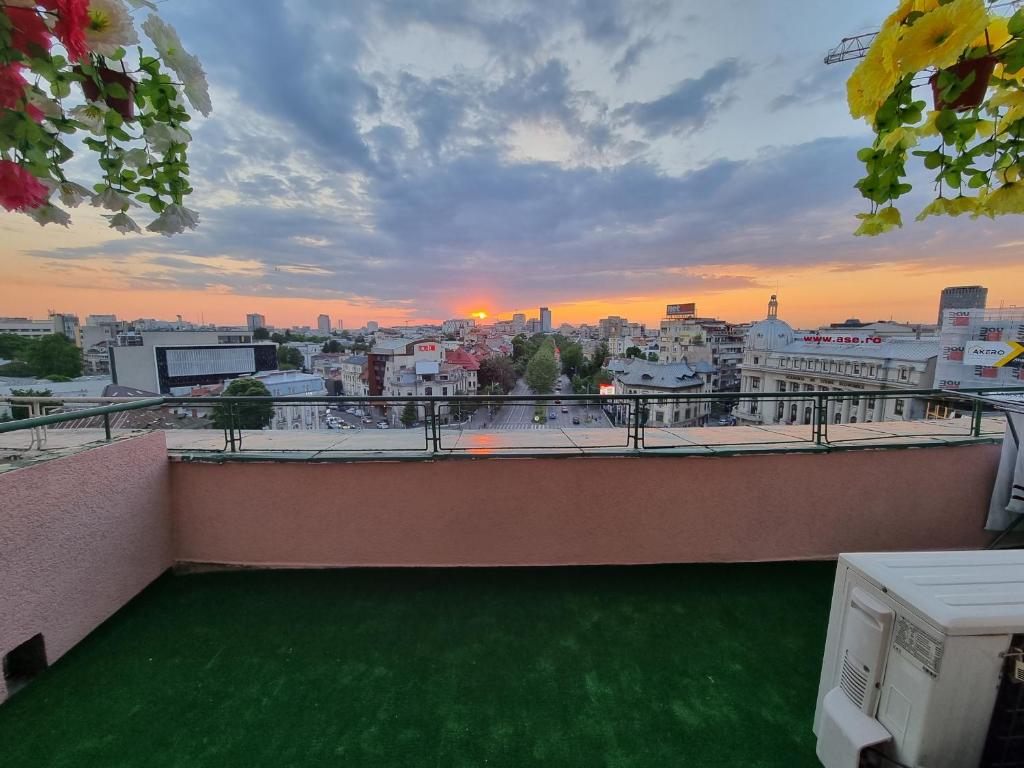 einen Balkon mit Blick auf eine Stadt bei Sonnenuntergang in der Unterkunft Panorama view with terrace in Bukarest