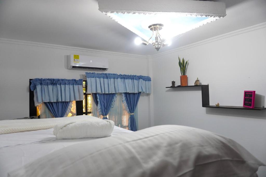 a bedroom with a white bed with blue curtains at Hostal Castañeda in San José del Guaviare