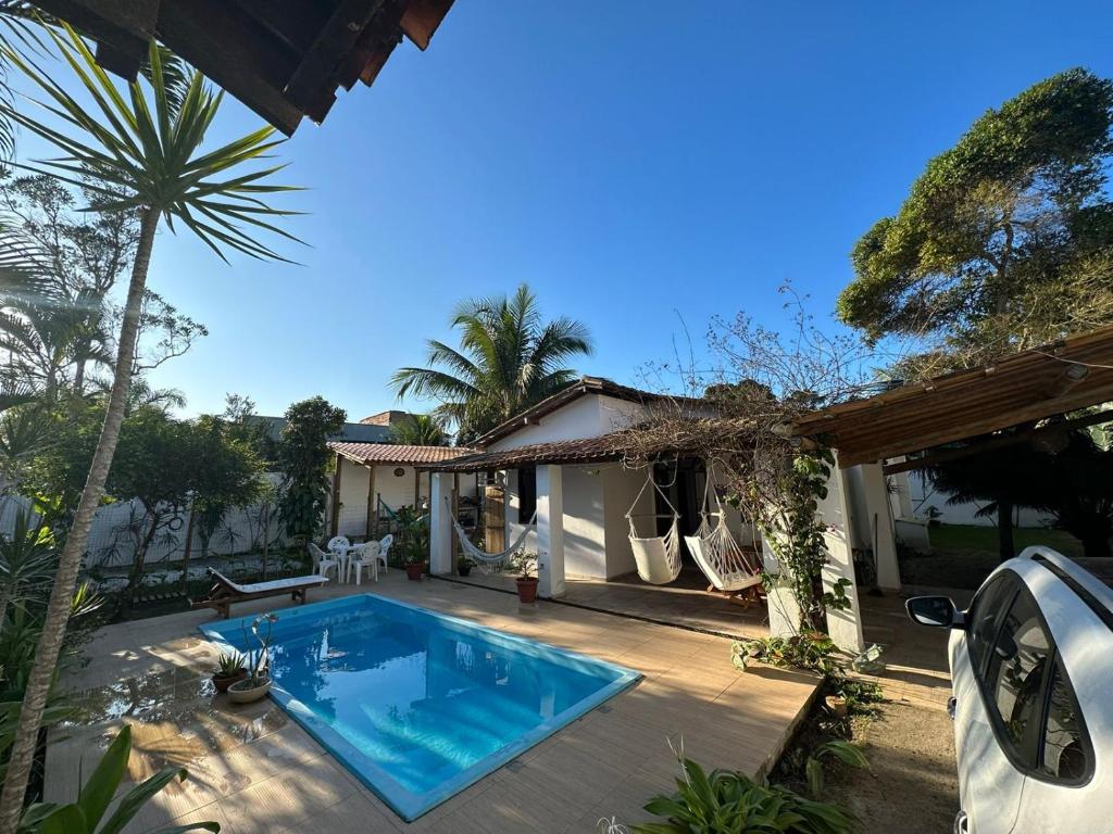 un patio trasero con piscina y una casa en Casa Tropical Arraial D' Ajuda, en Arraial d'Ajuda
