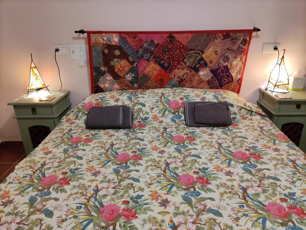 un letto con piumone fiorito e due comodini di Casa Picasso a Ítrabo