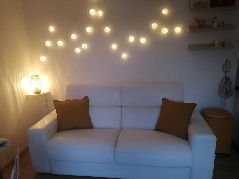 - un canapé blanc dans un salon avec des lumières sur le mur dans l'établissement Studio Les petites poules, à Saint-Lyphard