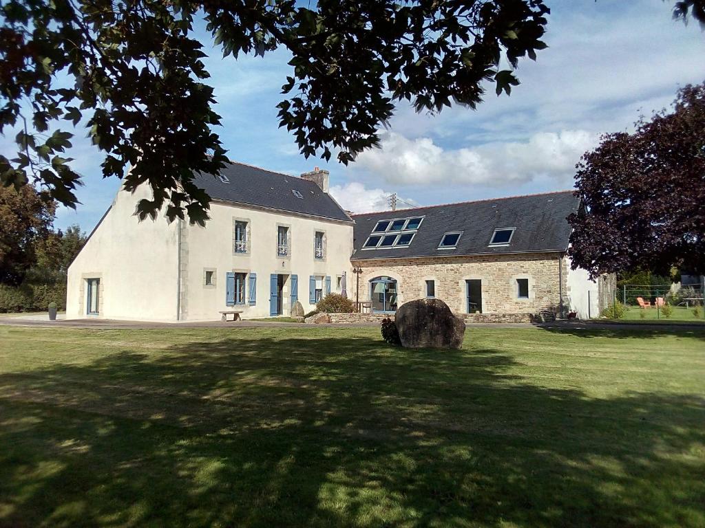 a large white building on a grass field at Gite de Kerantum in Mahalon