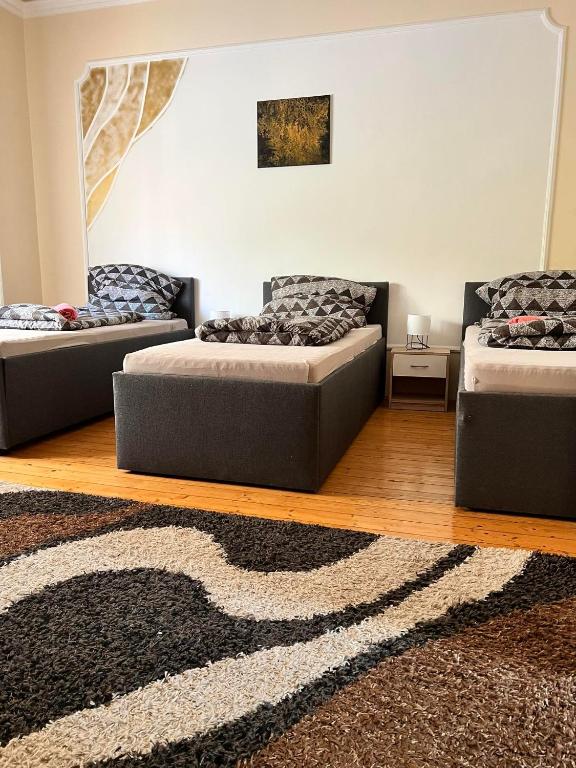 three beds sitting in a room with a rug at Best Price Guesthouse in Szeged