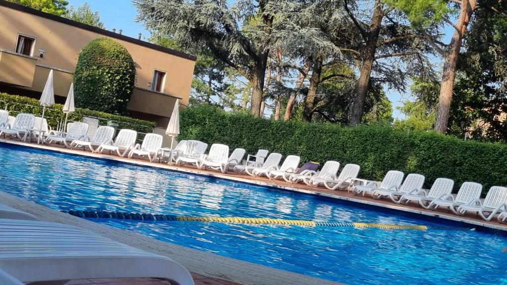 einen Pool mit weißen Liegestühlen neben einem Gebäude in der Unterkunft Casa al Lago Leone d'Oro in Peschiera del Garda