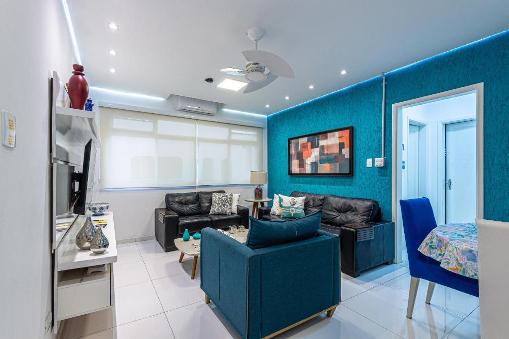 a living room with a couch and a blue wall at Apê Descolado no Guarujá - Enseada in Guarujá