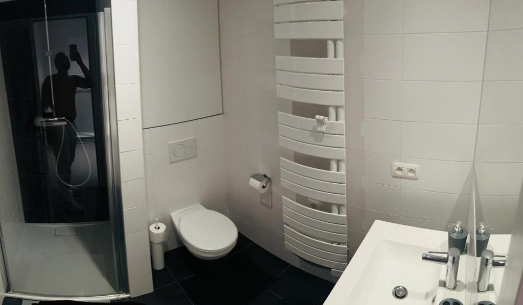 a white bathroom with a toilet and a sink at Élégant appartement (quartier européen) in Brussels
