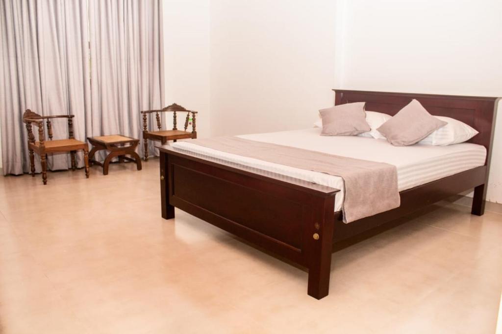 sypialnia z łóżkiem i krzesłami w pokoju w obiekcie Villa Double T Residence w mieście Ambalangoda