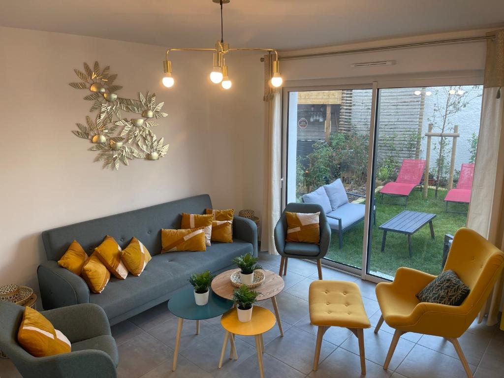 Una sala de estar con un sofá azul y sillas. en Villa des Cerisiers, en Saint-Nazaire