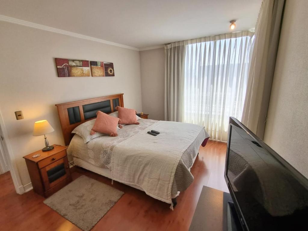 Schlafzimmer mit einem Bett und einem Flachbild-TV in der Unterkunft Santiago Moneda Suites in Santiago