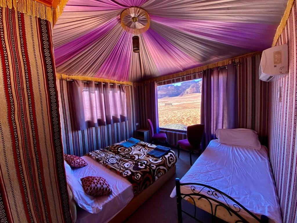 a bedroom with a tent with a bed and a window at Rum Roza luxury camp in Wadi Rum