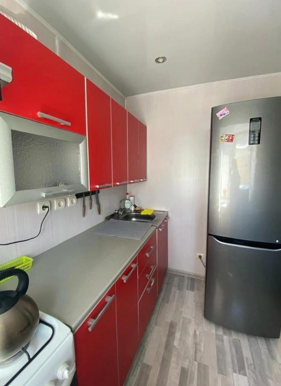 Nelwood Apartment في Socorro: مطبخ مع دواليب حمراء وثلاجة ستانلس ستيل