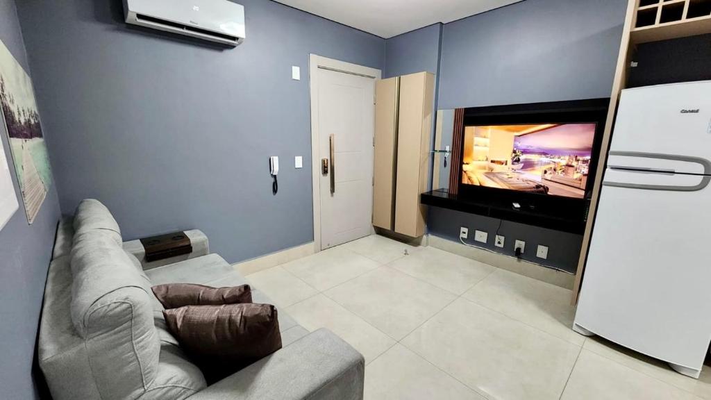 a living room with a couch and a flat screen tv at Loft Família c/ 2 Quartos e Lava e Seca no Vertigo in Campo Grande