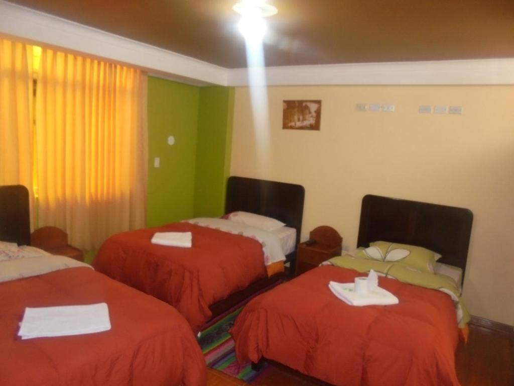 Habitación de hotel con 2 camas con sábanas rojas en hostal andina joya, en Puno