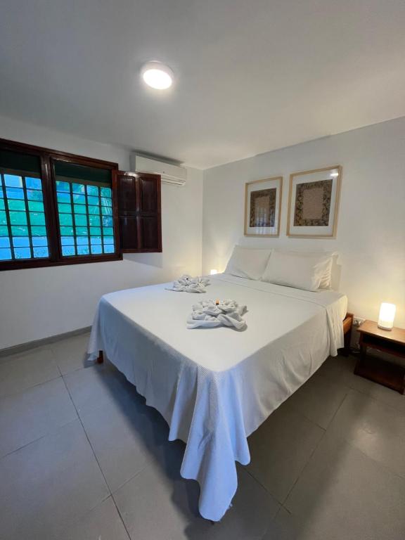 Bitingui Praia Hotel في جاباراتينغا: غرفة نوم بسرير ابيض كبير مع شراشف بيضاء
