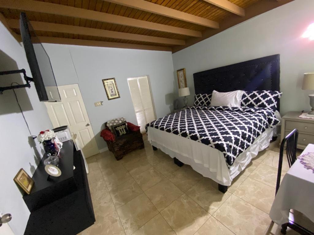 una camera da letto con un letto con un piumone bianco e nero di Portmore - Cheerful Private Bedroom with Fan only or AC - Choose your room a Portmore