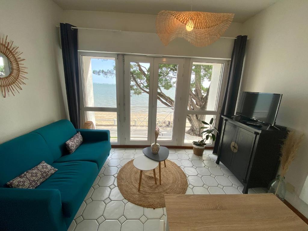 un salon avec un canapé bleu et une télévision dans l'établissement Appartement vue mer île d'Oléron, à Saint-Trojan-les-Bains