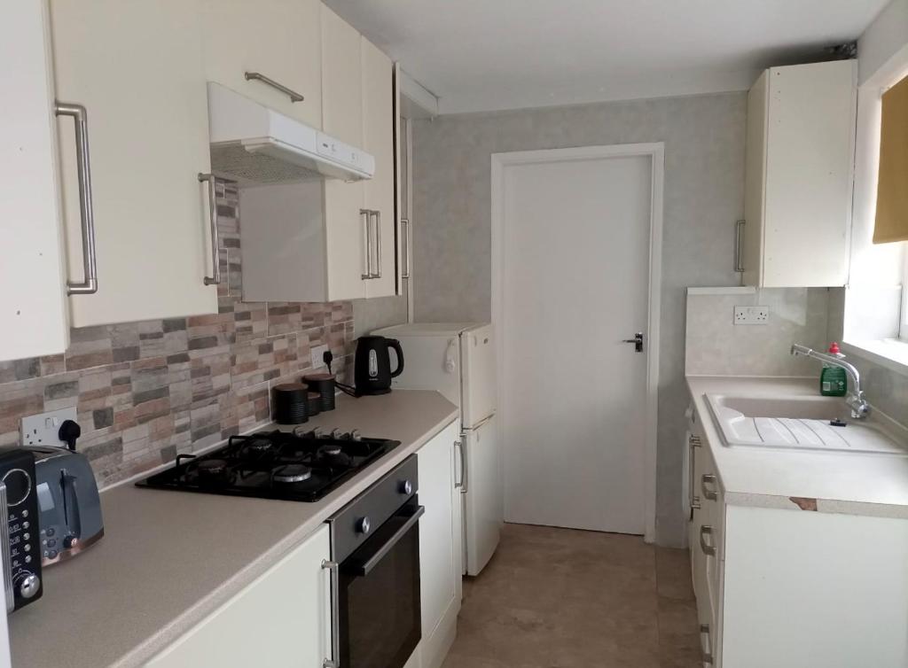 a kitchen with white cabinets and a stove top oven at Beautiful Town Centre home in Middlesbrough