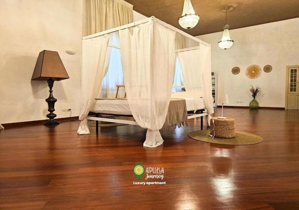 Schlafzimmer mit einem Bett mit Vorhängen auf einem Holzboden in der Unterkunft Apulia Journey - Manzoni 11 in Bari