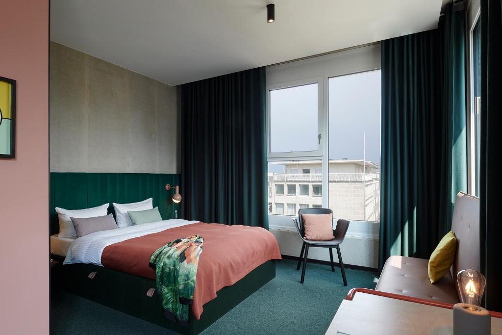 a hotel room with a bed and a large window at Basecamp Hotel Dortmund in Dortmund