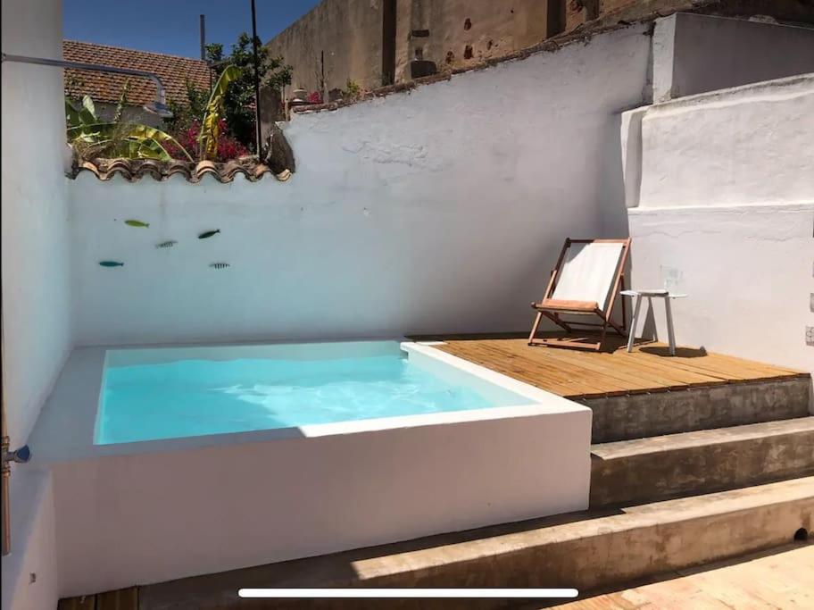 uma piscina com uma cadeira ao lado de algumas escadas em Traditional townhouse with private patio and pool em Portimão