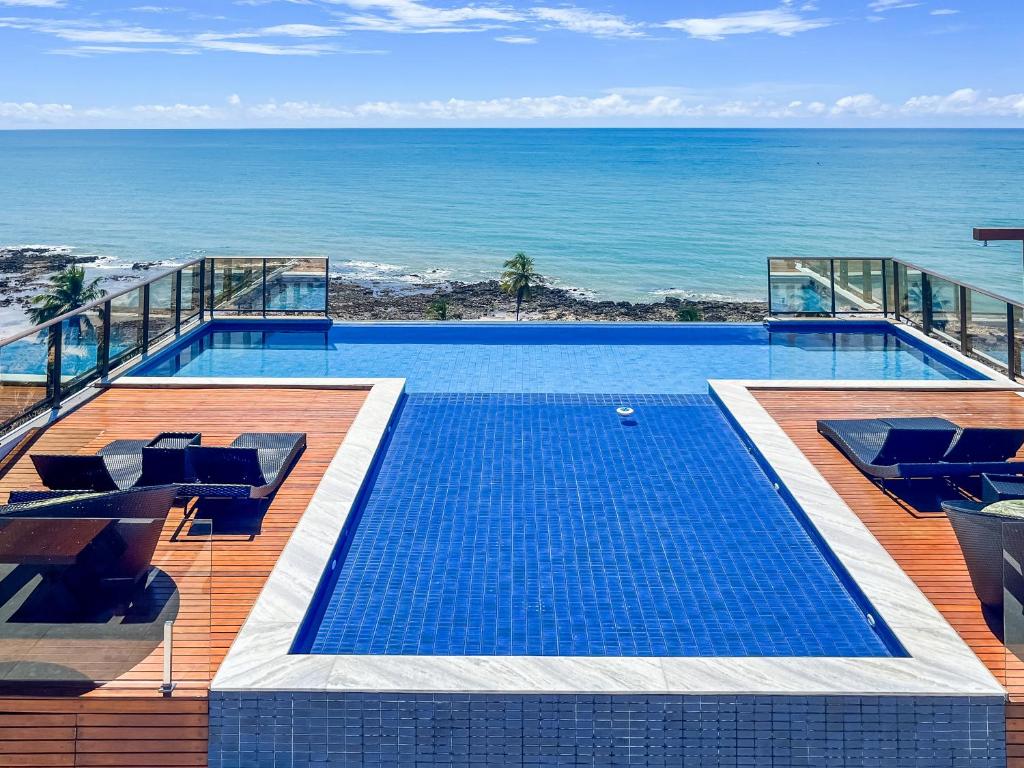a swimming pool with a view of the ocean at FLATS ENSEADA Do SOL in Jacumã