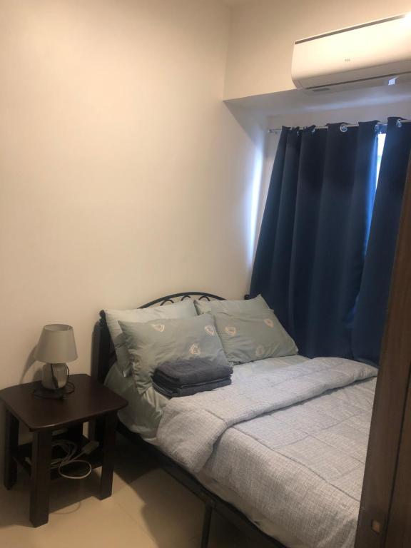 a bedroom with a bed with blue curtains and a table at Staycation in Manila