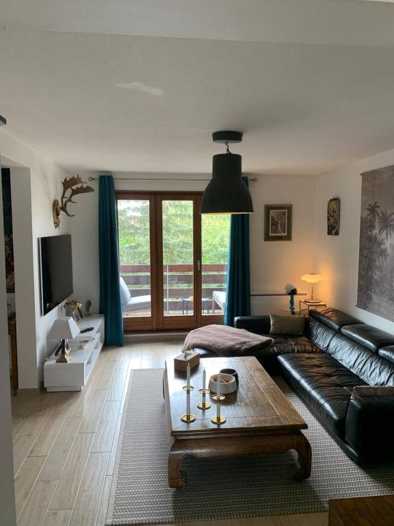 a living room with a black leather couch and a table at Appartement spacieux et lumineux in Sélestat