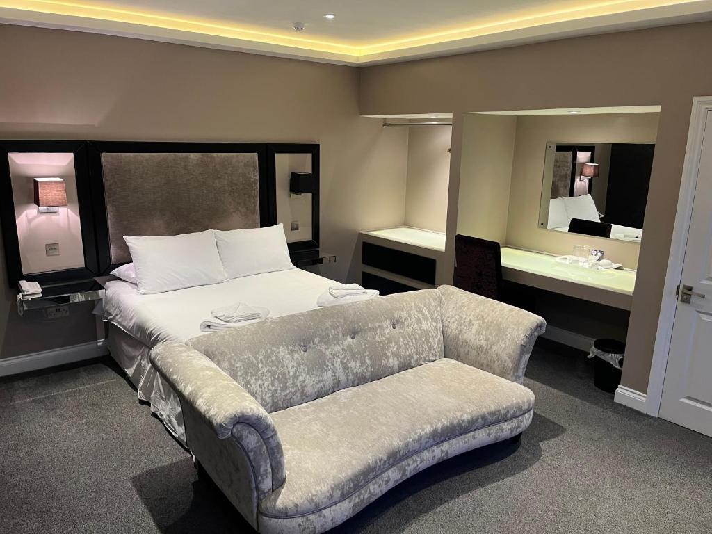 a bedroom with a bed and a couch and a mirror at Limes hotel in Needham Market