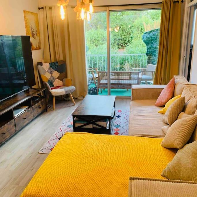 un salon avec un canapé jaune et une télévision dans l'établissement Appartement entier vue dégagée avec parking, à Montpellier