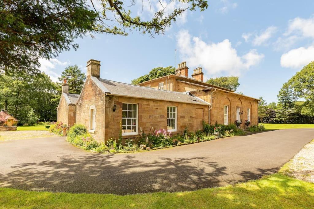 una vieja casa de ladrillo con una entrada delante de ella en Luxury Scottish Manor house + jacuzzi + bbq cabin + helipad, en Maybole