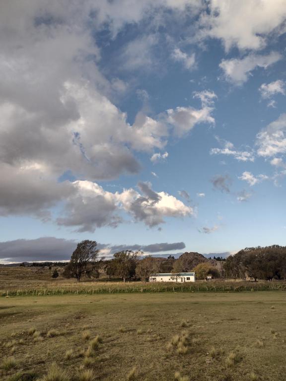een veld met een huis en een bewolkte lucht bij Posada Casablanca in La Carolina