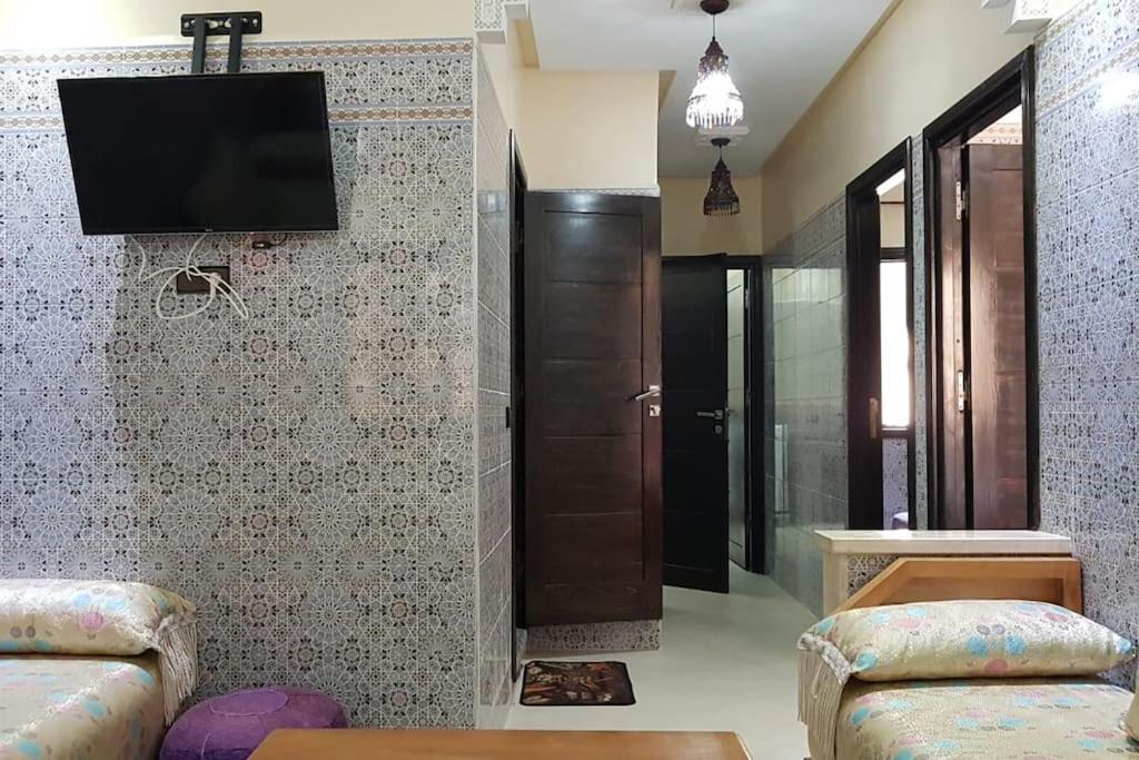 a living room with a tv on a wall at Appartement au 1er étage in El Jadida