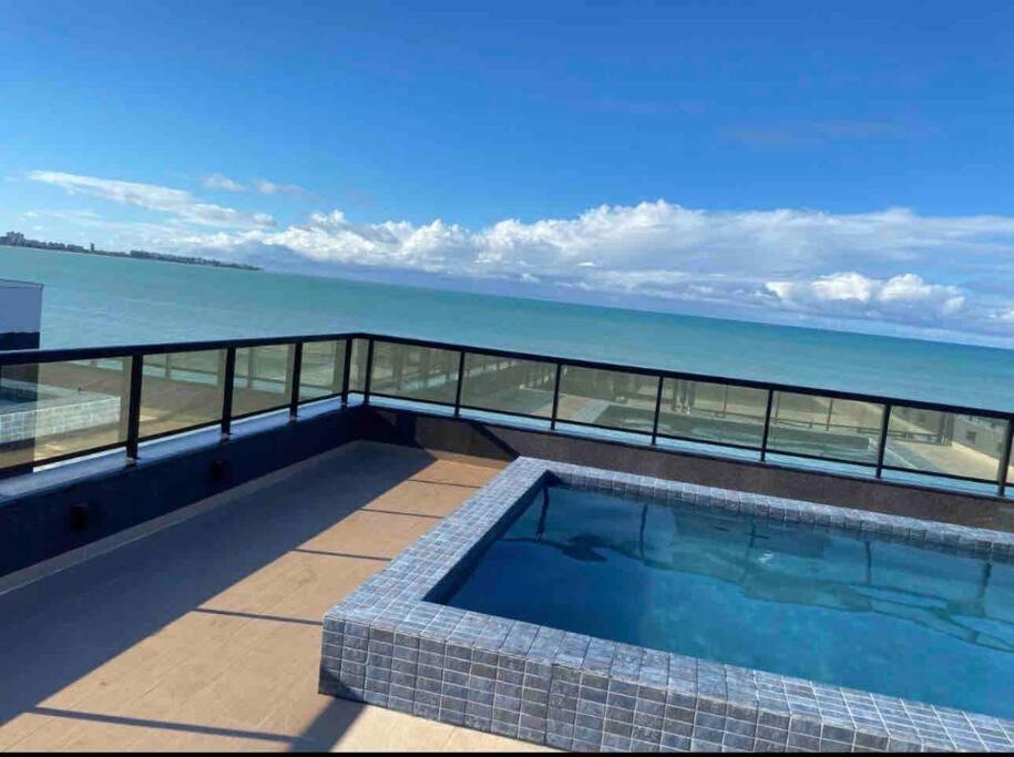 a swimming pool on the roof of a building overlooking the ocean at FLAT Pé na areia no Bessa in João Pessoa