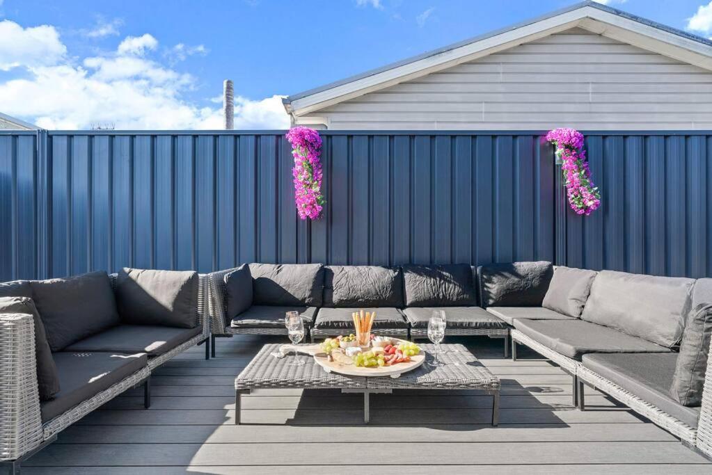 a patio with couches and a table with a bowl of fruit at The Seachange - Brand New, Beachy Family Retreat. in Ettalong Beach