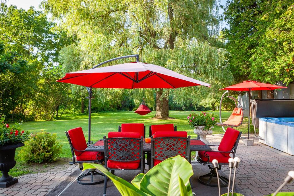 Dundas的住宿－Nature Oasis Mar Suite，配有红色椅子和遮阳伞的天井桌子