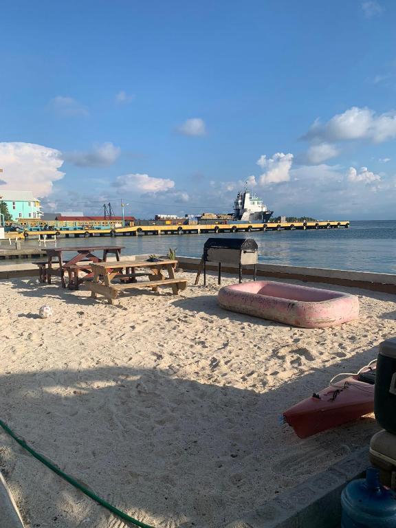 a sandy beach with picnic tables and a pier at Paradise Divers Hotel in Utila