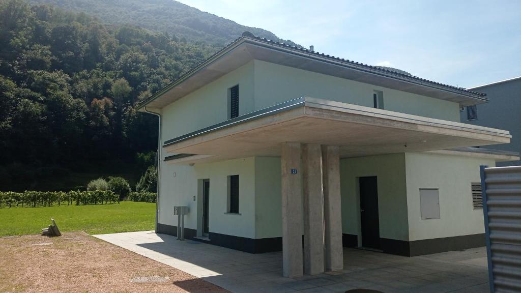uma casa branca com pilares em frente a um quintal em 33 em Cadenazzo