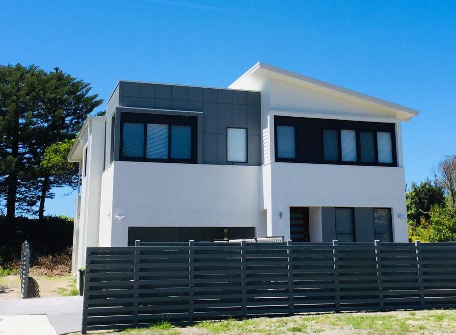 una casa blanca con ventanas negras y una valla en Sea & Sun Beach House, en Norah